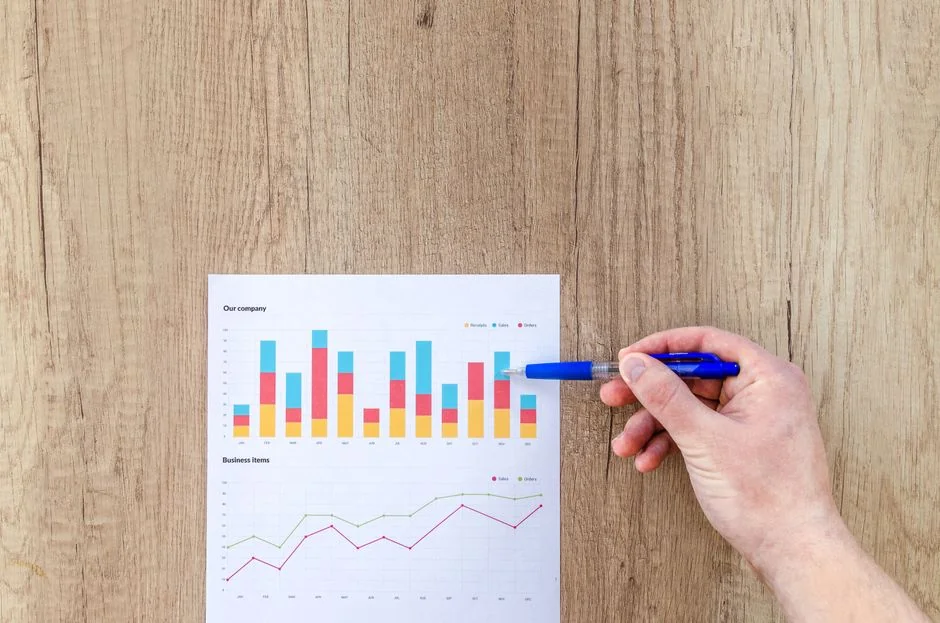 Des mains échangent autour d’une stratégie marketing, avec des graphiques, dans un bureau.